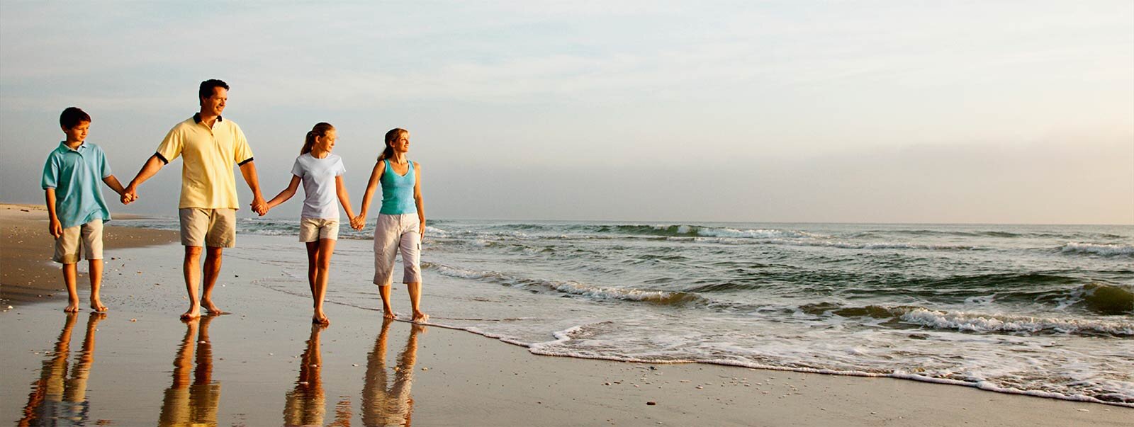 Mother, father and two children walking on the beach